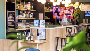 Angolo bar con scaffali in legno, una televisione e sgabelli da bar.