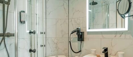 Une salle de bain moderne avec une douche à parois de verre, des toilettes blanches et un lavabo sur colonne.