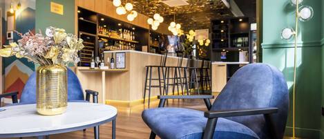 A modern bar area with a round table, blue chairs, and a decorative vase.
