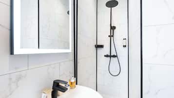 A modern bathroom with a white marble tile wall, a black showerhead, and a white sink with a mirror above it.