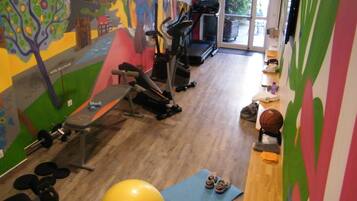 A gym with exercise equipment, a treadmill, and a colorful mural on the wall.