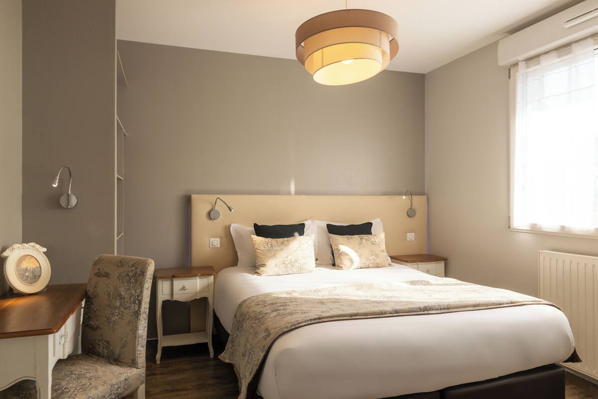A bedroom with a large bed, bedside tables, a chair, and a ceiling light fixture.