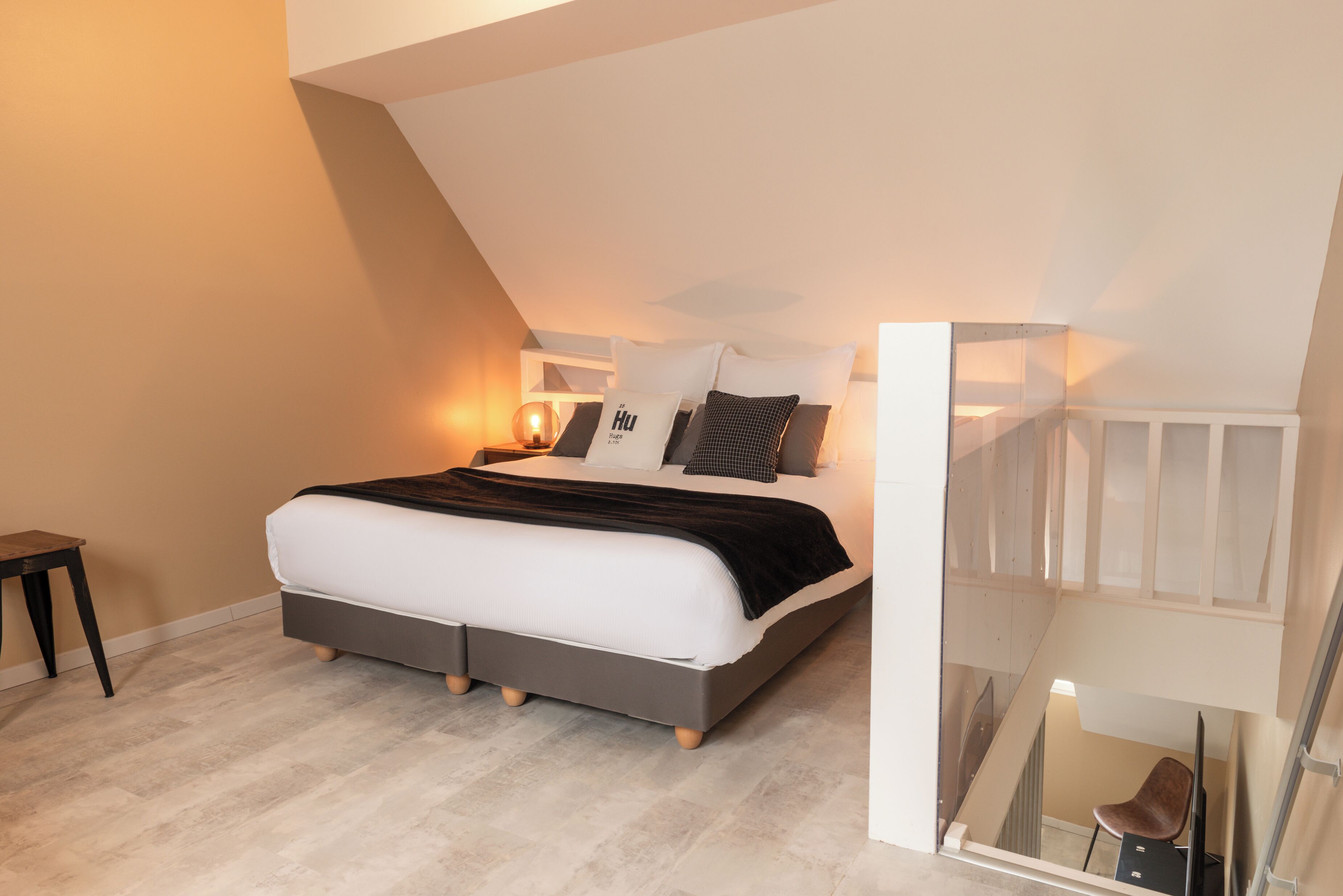 A modern bedroom with a bed, bedside tables, and a staircase.
