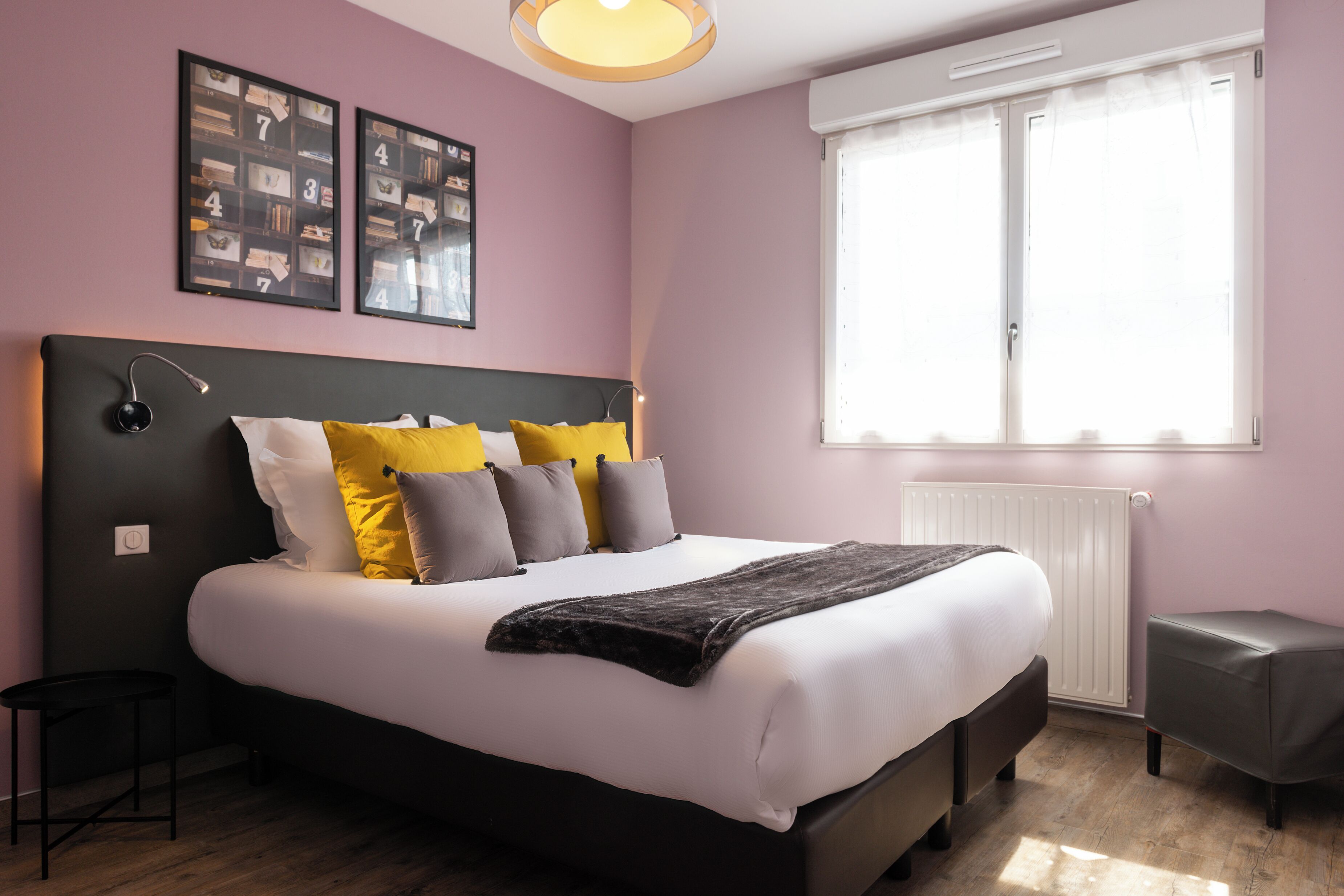 Een slaapkamer met een bed, nachtkastjes, een raam en decoratieve wandkunst.