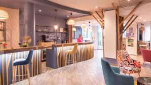 Un área de bar moderna con mostrador, taburetes y un espacio de estar con sillas.