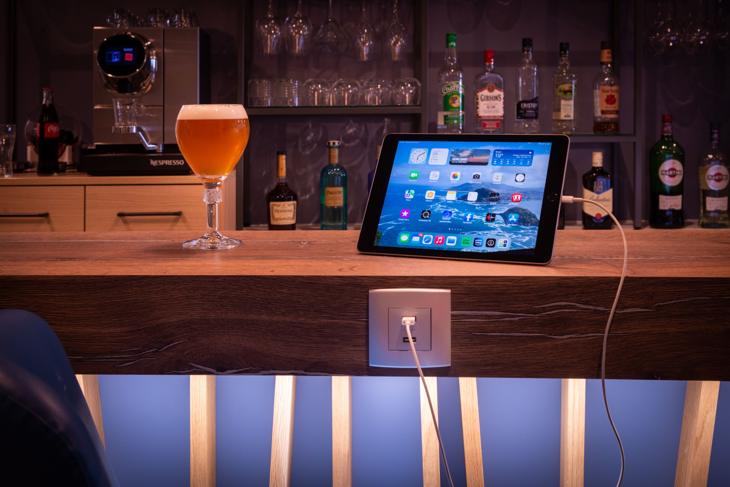 Angolo bar con un tablet che mostra diverse applicazioni, un bicchiere di birra e una macchina Nespresso.