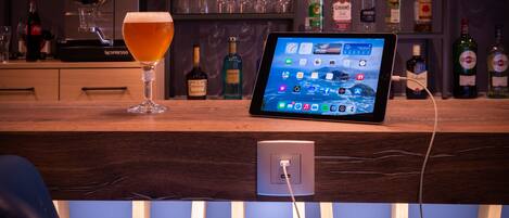 Angolo bar con un tablet che mostra diverse applicazioni, un bicchiere di birra e una macchina Nespresso.