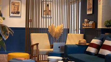 A modern living room with a blue sofa, a wooden chair, a laptop, and a decorative vase.