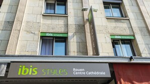 Ein Gebäudefassad mit 'ibis styles'-Beschilderung und einem Schild mit der Aufschrift 'Rouen Centre Cathédrale'.