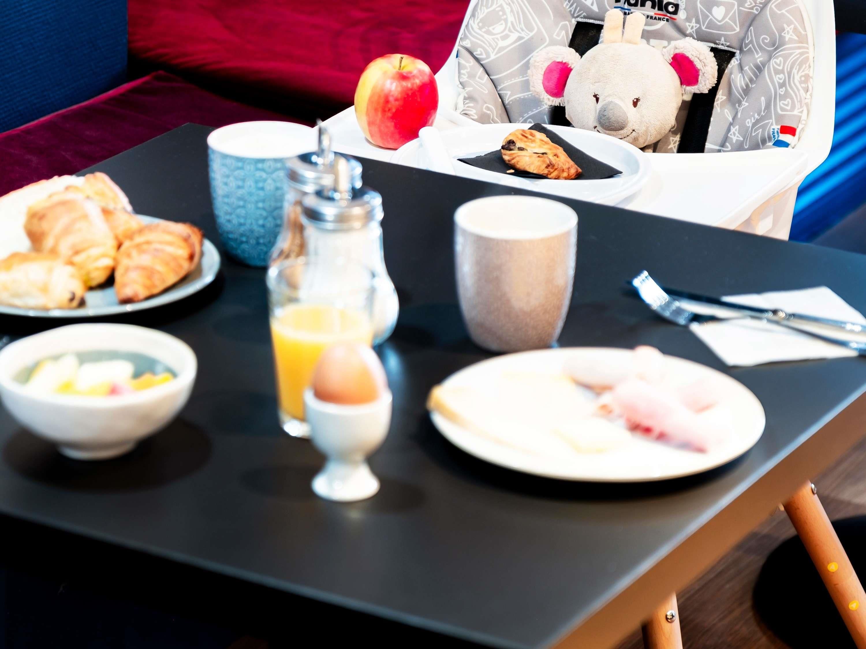 Ein Frühstücksbuffet mit Croissants, einer Obstschale, einem Glas Orangensaft, einer Tasse und einem Teller mit Gebäck.