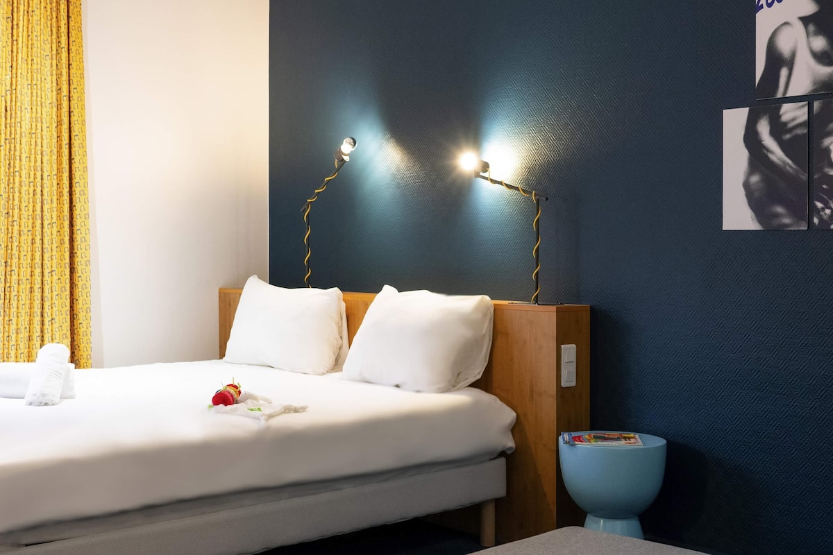 Ein ordentlich bezogenes Bett mit weißen Leinen, einem Holzkopfende und zwei Nachttischlampen.