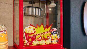 Une machine à pop-corn rouge, ornée d’un personnage de dessin animé, avec les inscriptions « POP CORN » et « SERVICE TRAITEUR ROYAL par Hooters ».