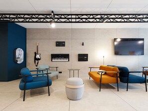 Et moderne loungeområde med møbler, en guitar, elektronisk musikudstyr og et fjernsyn.