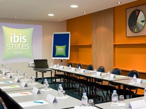 Ein Konferenzraum mit einem langen Tisch, Namensschildern, Wasserflaschen und einem Laptop.