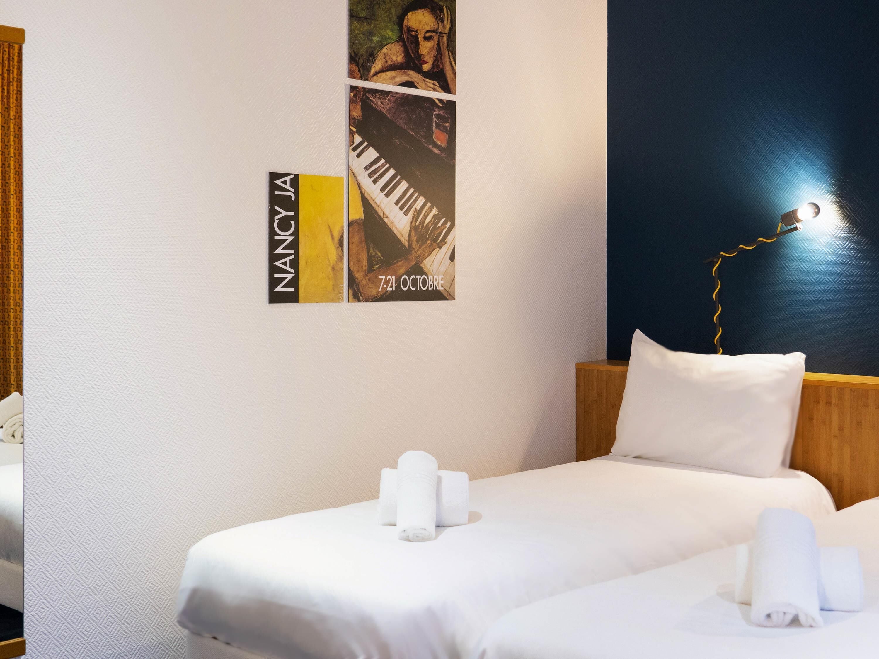 A hotel room with a bed, pillows, a wall clock, and a poster.