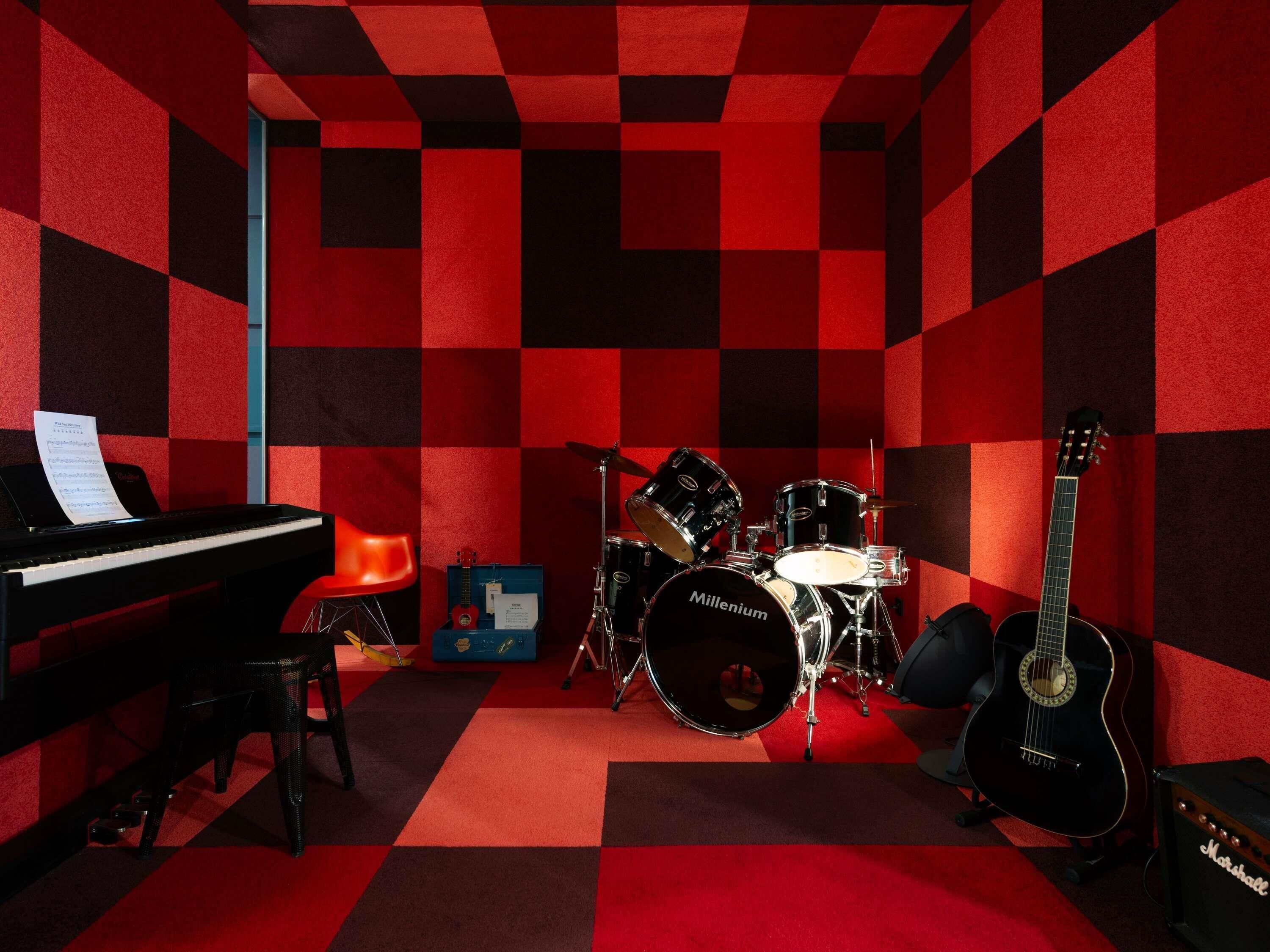 A recording studio with a piano, drum set, guitar, and amplifier.