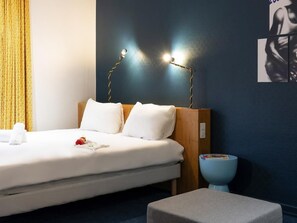 Ein Hotelzimmer mit Bett, Nachttisch, Wandlampe und einer blauen Akzentwand.
