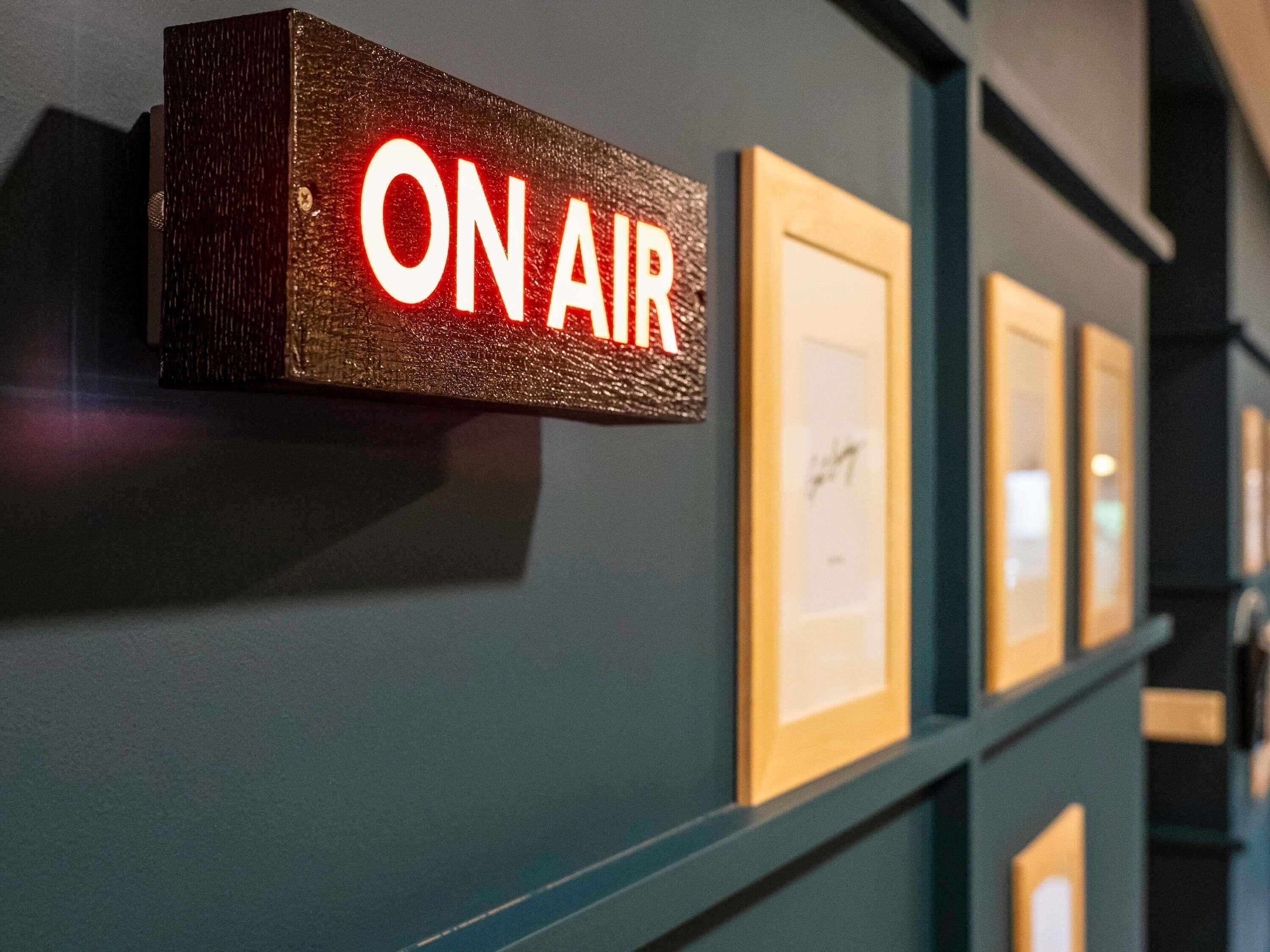Una pared con un cartel que dice 'ON AIR' y varias fotografías enmarcadas.