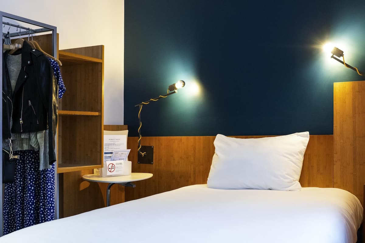 Ein Hotelzimmer mit einem Bett, einem Kleiderschrank, einem kleinen Tisch und zwei Wandleuchten.