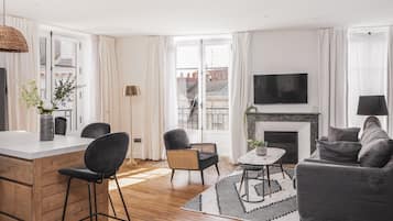 A modern living room with a fireplace, a dining area, and a seating area with a sofa and chairs.