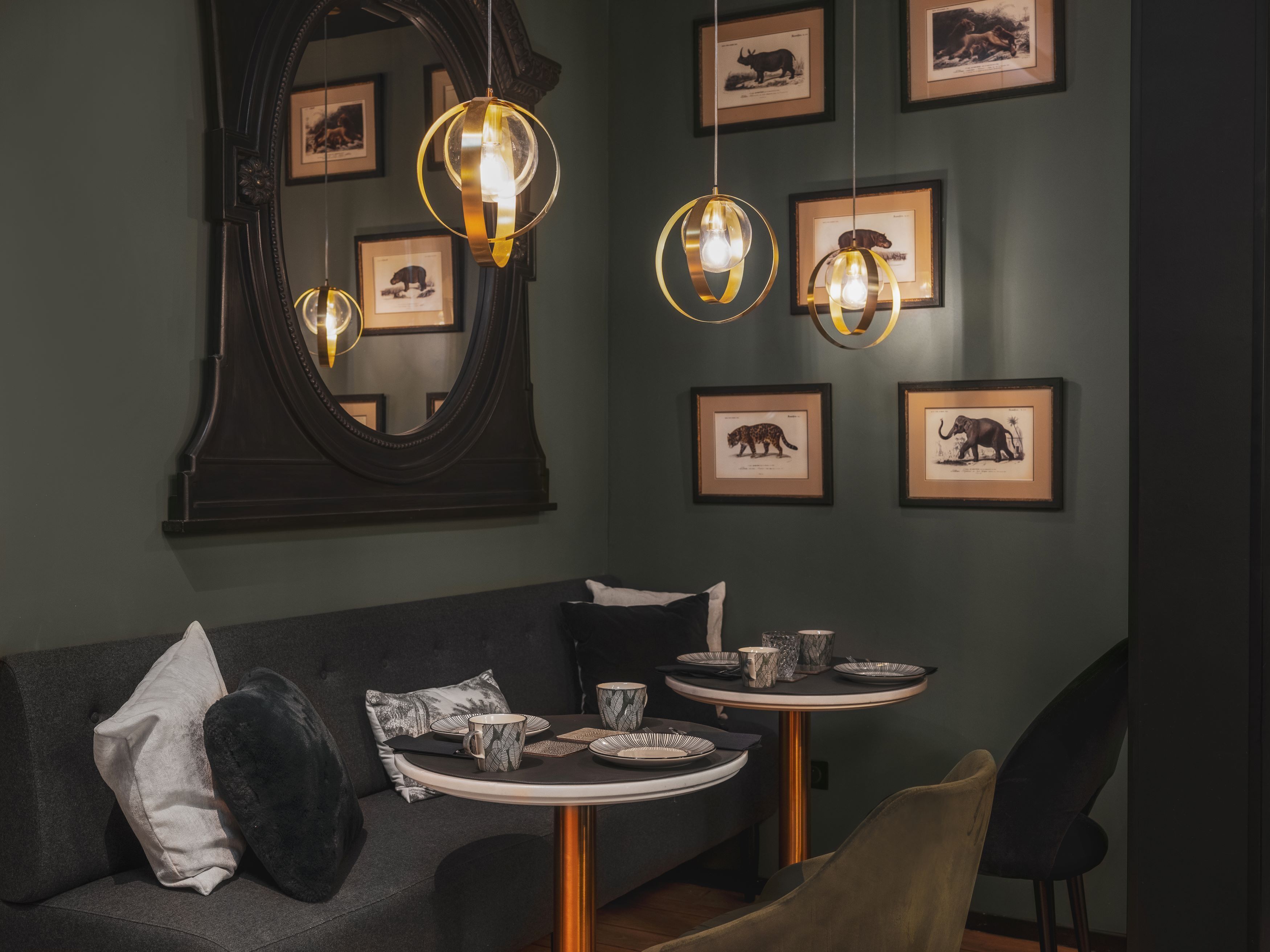 Zona pranzo con un tavolo rotondo, un divano scuro e stampe di animali incorniciate alle pareti.