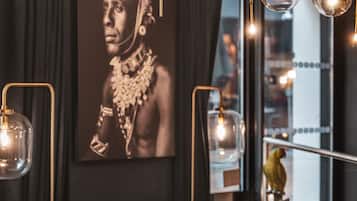 Una sala moderna con un sofá negro, cojines estampados, una mesa de centro redonda y una mesa de vidrio con un cuenco.