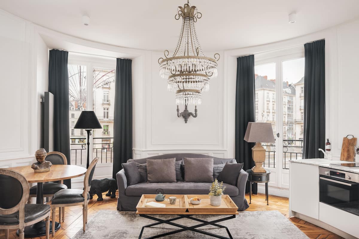 A modern living room with a grey sofa, wooden coffee table, and a chandelier.