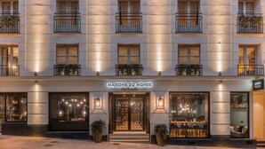Fachada de hotel con balcones, ventanas amplias y un letrero que dice 'MAISONS DU MONDE Hotel & Suites'.