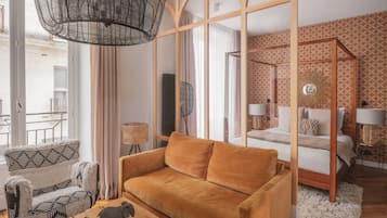 Quarto de hotel moderno com sofá, uma pequena estatueta de elefante, luminária trançada e cama com papel de parede estampado.