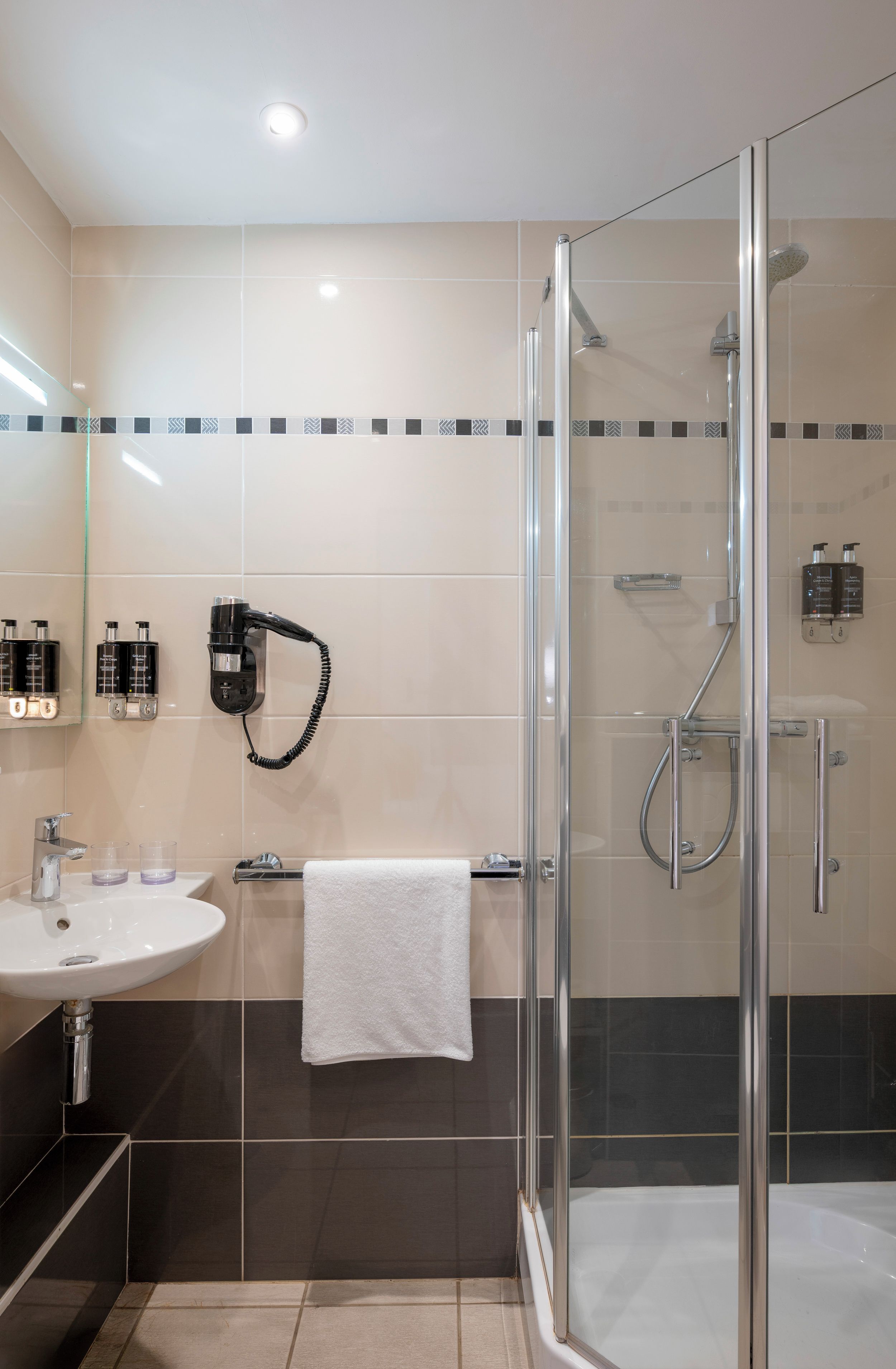 A modern bathroom with a glass-enclosed shower, a white sink, and a mirror.