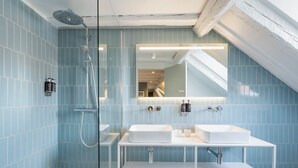 Un baño moderno con cabina de ducha de vidrio, dos lavamanos y un espejo grande.