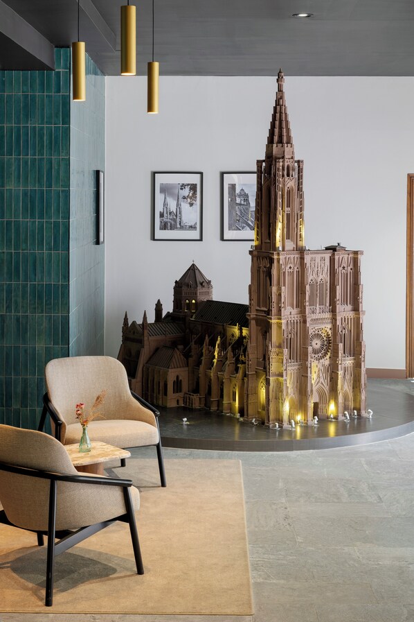 Un interior moderno con un gran modelo de catedral, dos cuadros enmarcados y una zona de estar con un jarrón.