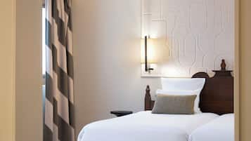 Quarto de hotel com cama, mesa de cabeceira, abajur e um painel decorativo na parede.