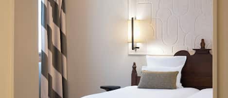 A hotel room with a bed, a nightstand, a lamp, and a decorative wall panel.