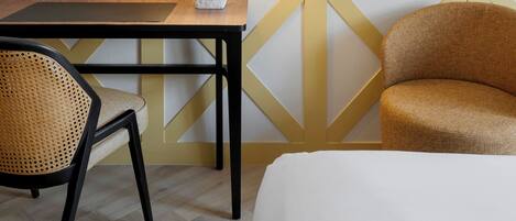 Una habitación con una cama, una mesa con lámpara, una silla y un sofá.