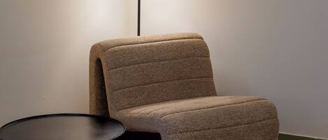 A modern room with a sofa, a small round table, and a floor lamp.