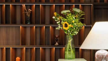 A modern interior with a wooden panel wall, a green vase with flowers, a white table, and patterned stools.
