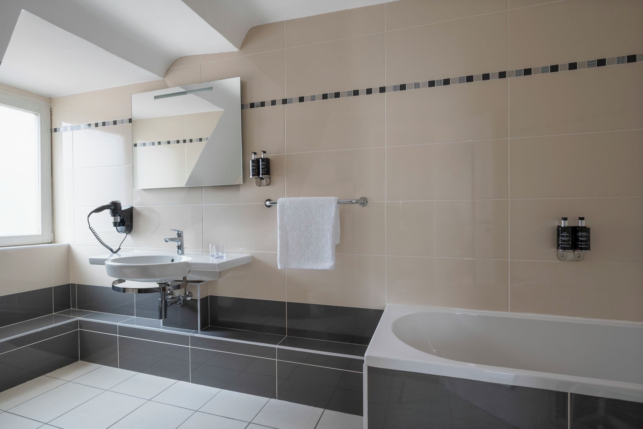 Un baño moderno con una bañera, dos lavamanos, un espejo y un perchero para toallas.