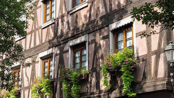 A multi-story building with traditional half-timbered architecture, featuring multiple windows with wooden frames and shutters.