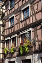 Un edificio tradicional con entramado de madera, múltiples ventanas y jardineras con flores.