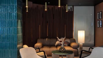 A modern lounge area with a sofa set, two armchairs, a coffee table, and pendant lighting.