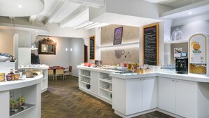 A modern breakfast area with white counters, a herringbone wood floor, and a mirror above the counter. - Hôtel de l'Europe by Happyculture (Strasbourg)