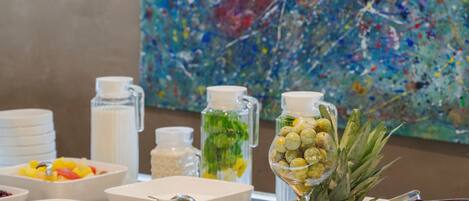 A buffet with various food items and a colorful abstract painting in the background.