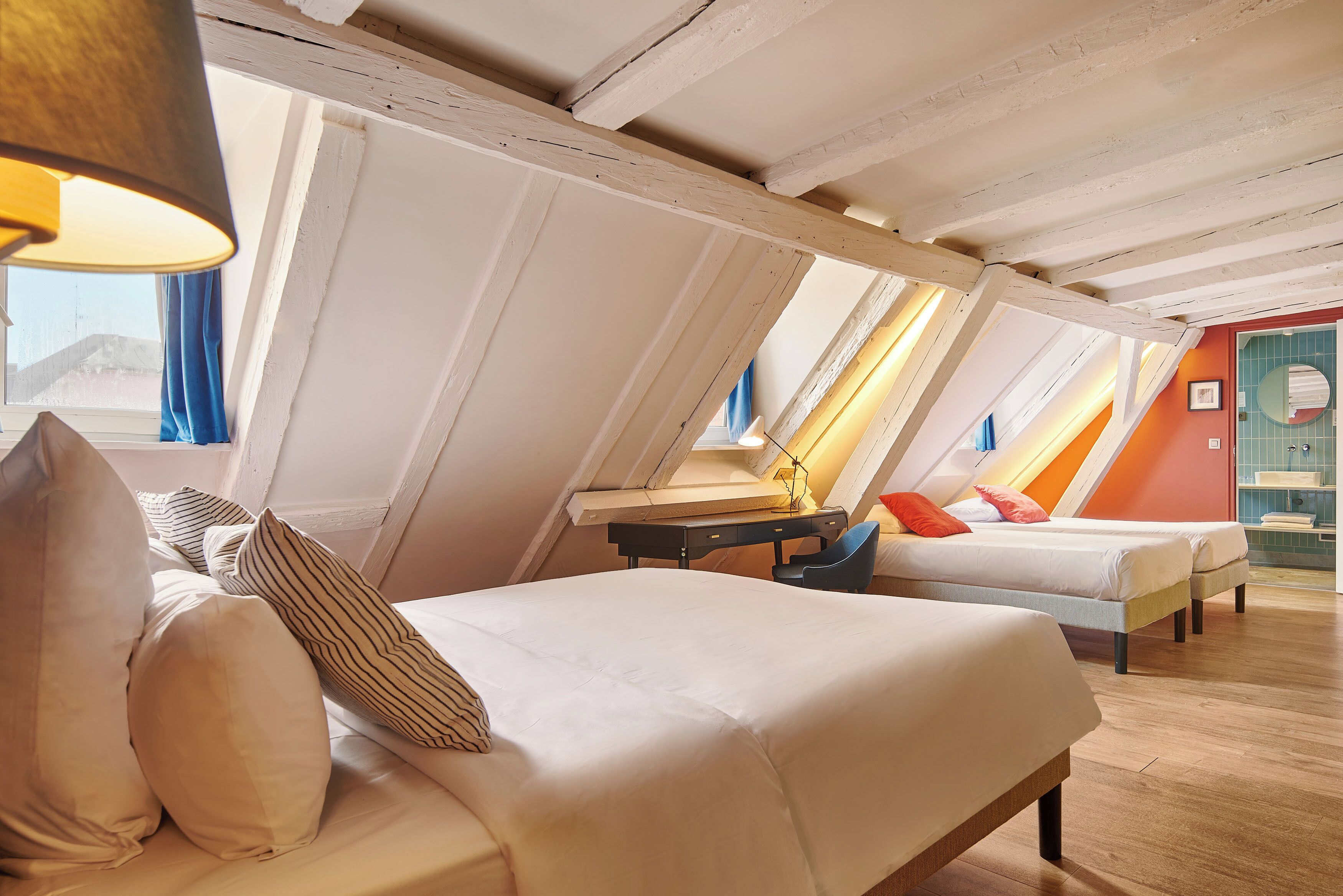 Une chambre avec deux lits, un bureau et une fenêtre.