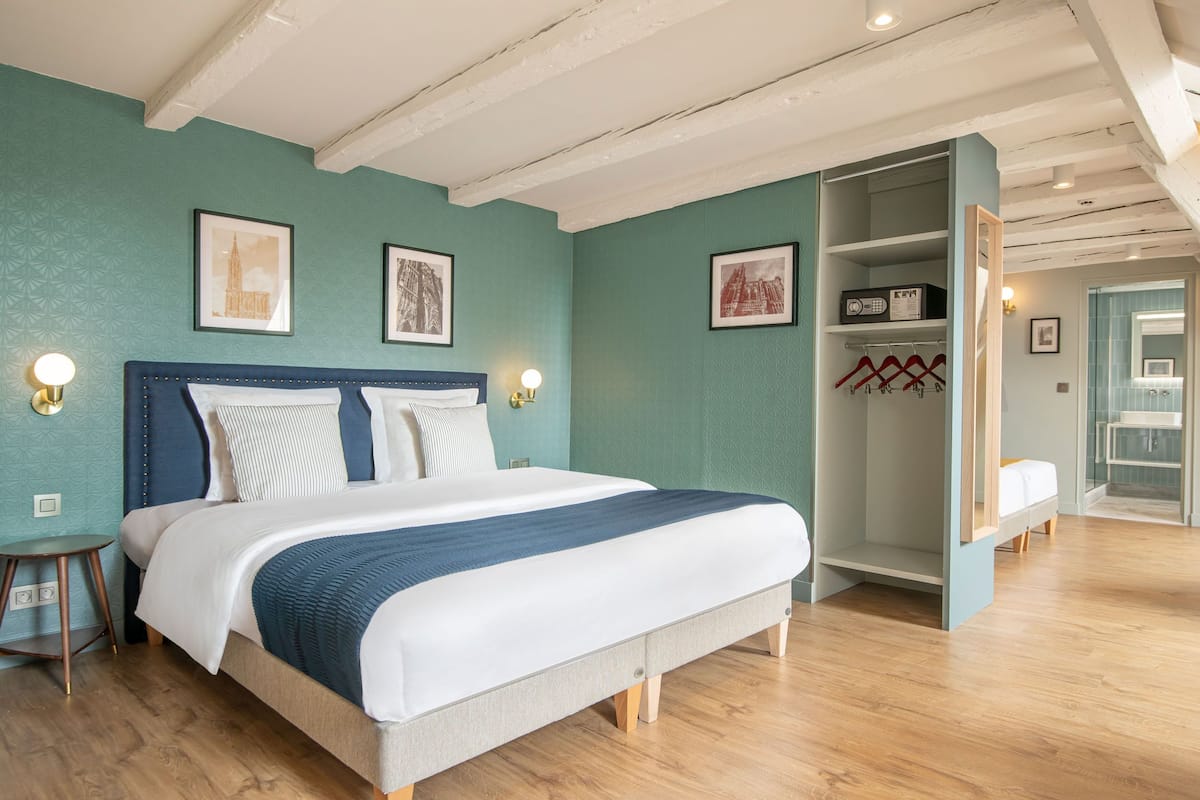 A bedroom with a large bed, a wardrobe, and a small bedside table.