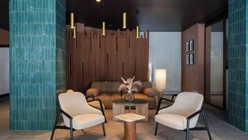 Uma área de estar moderna com um sofá, duas poltronas, uma mesa de centro e iluminação pendente.