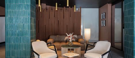 A modern lounge area with a sofa, two armchairs, a coffee table, and pendant lighting.