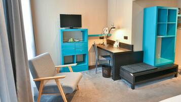 Una habitación de hotel con escritorio, silla, televisor y un amplio armario azul.
