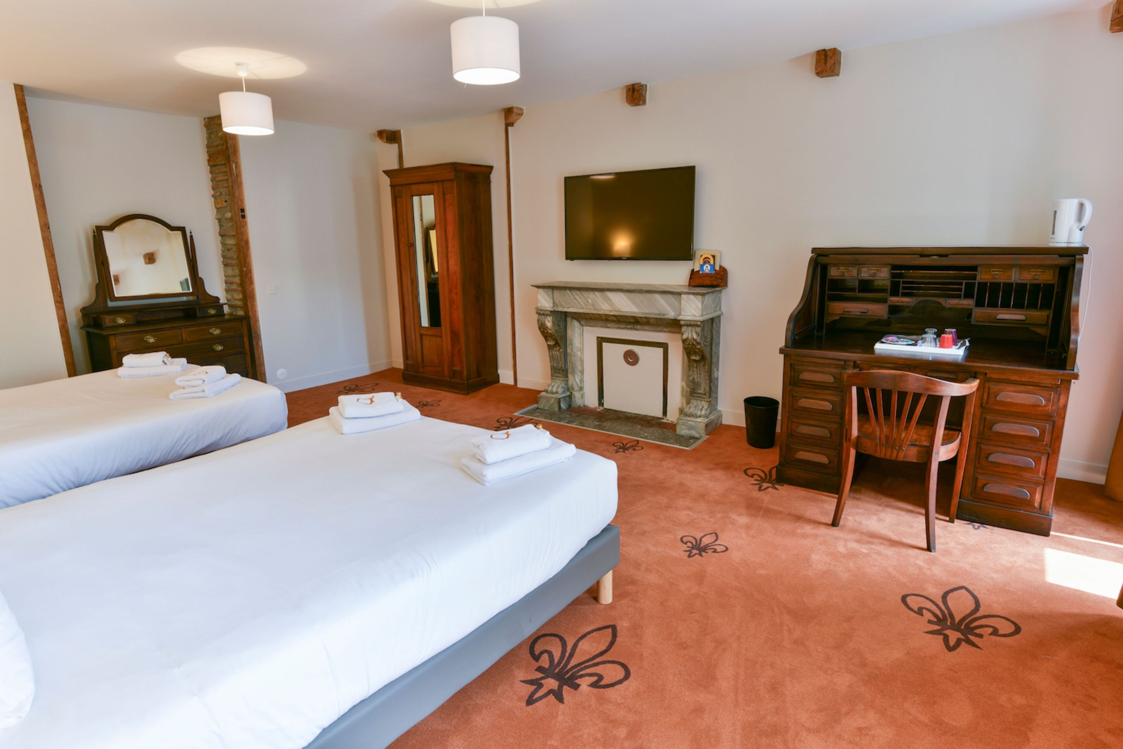 Une chambre d’hôtel avec deux lits, un bureau, une télévision et une cheminée.