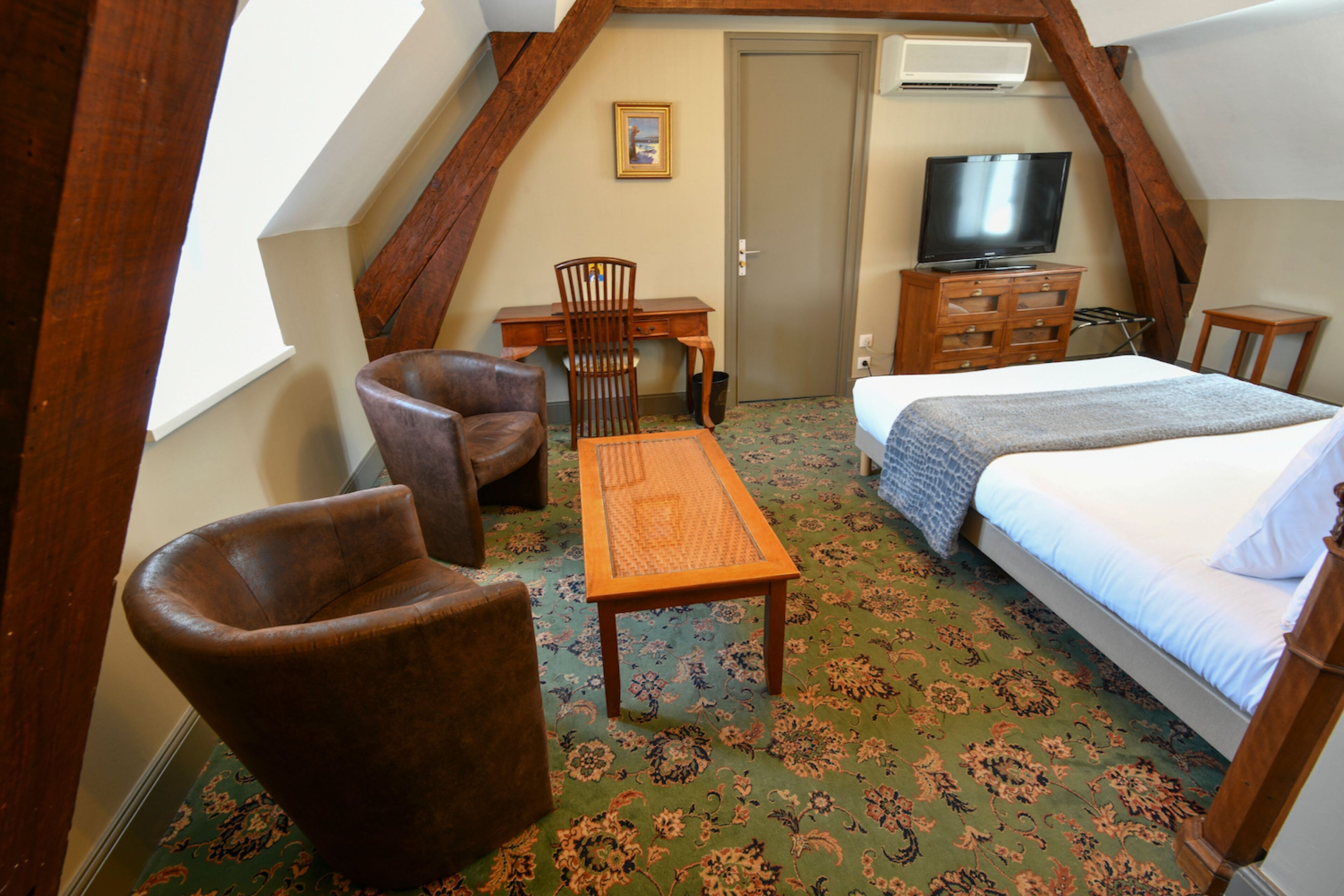 A room with a bed, a desk, a chair, and a television.